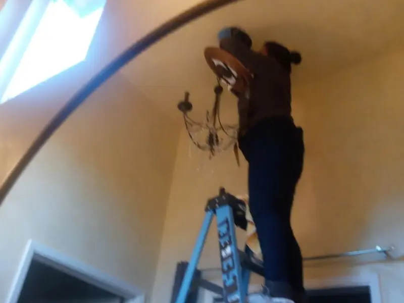 Electrician installing a chandelier in a Roseburg residence